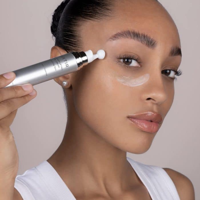 woman applying eye cream under her eye
