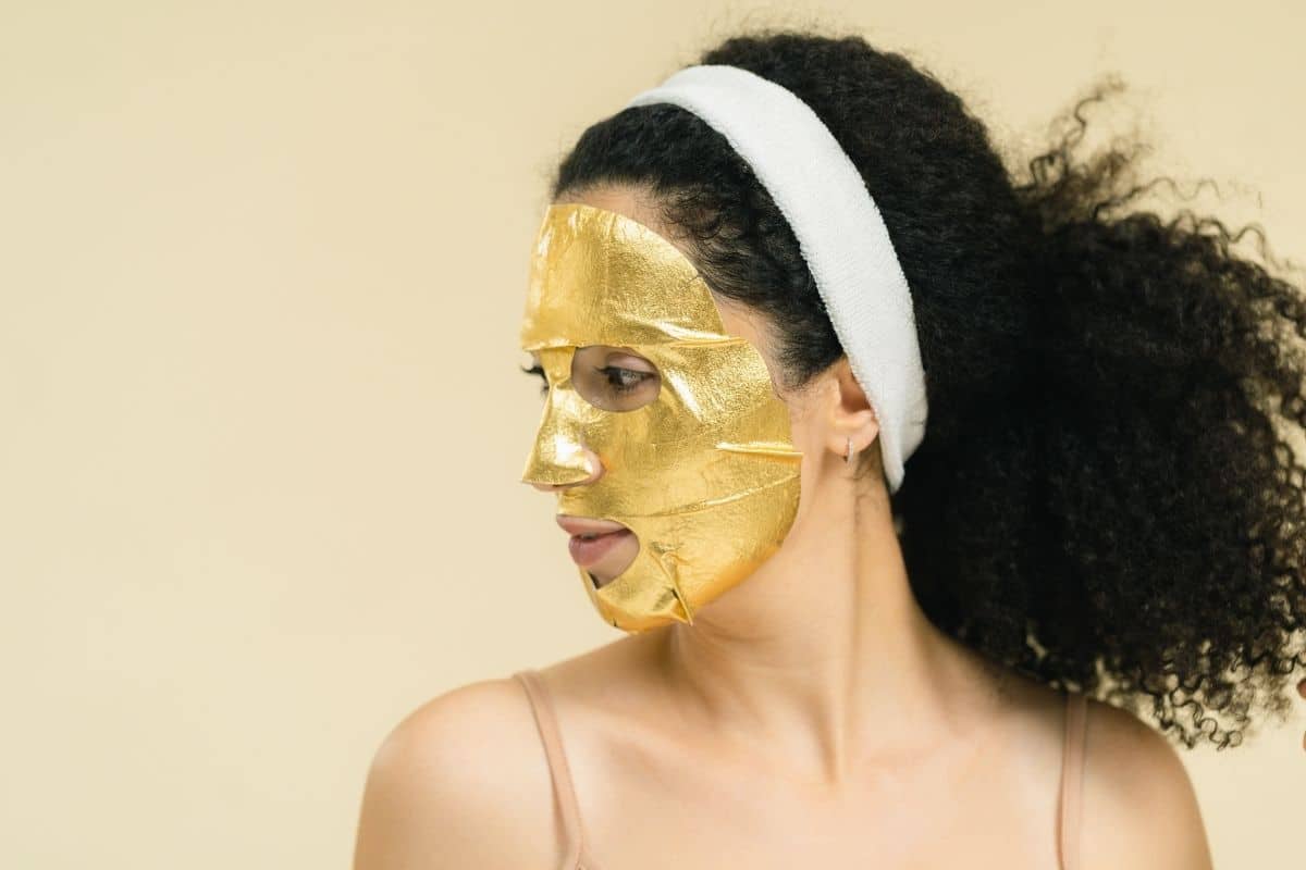 Woman with gold sheet mask on her face.