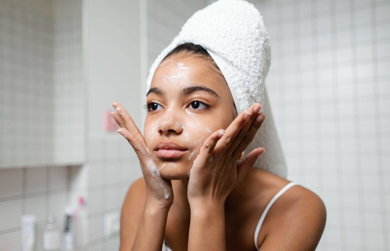 woman with towel on her head washing her face